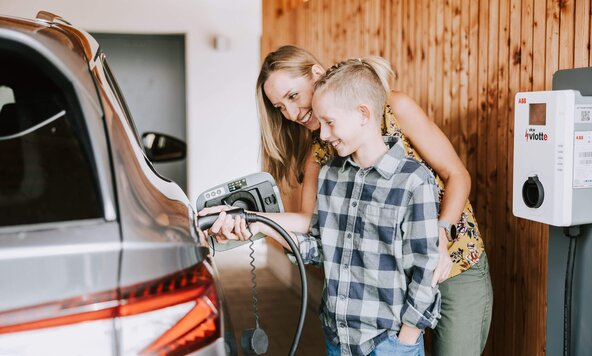 Mutter zeigt ihrem Sohn, wie man ein E-Auto zuhause auflädt
