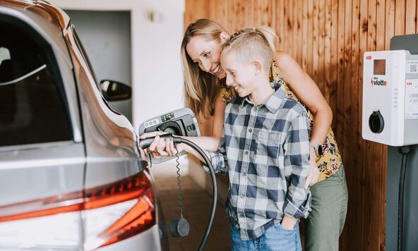 Mutter zeigt ihrem Sohn, wie man ein E-Auto zuhause auflädt